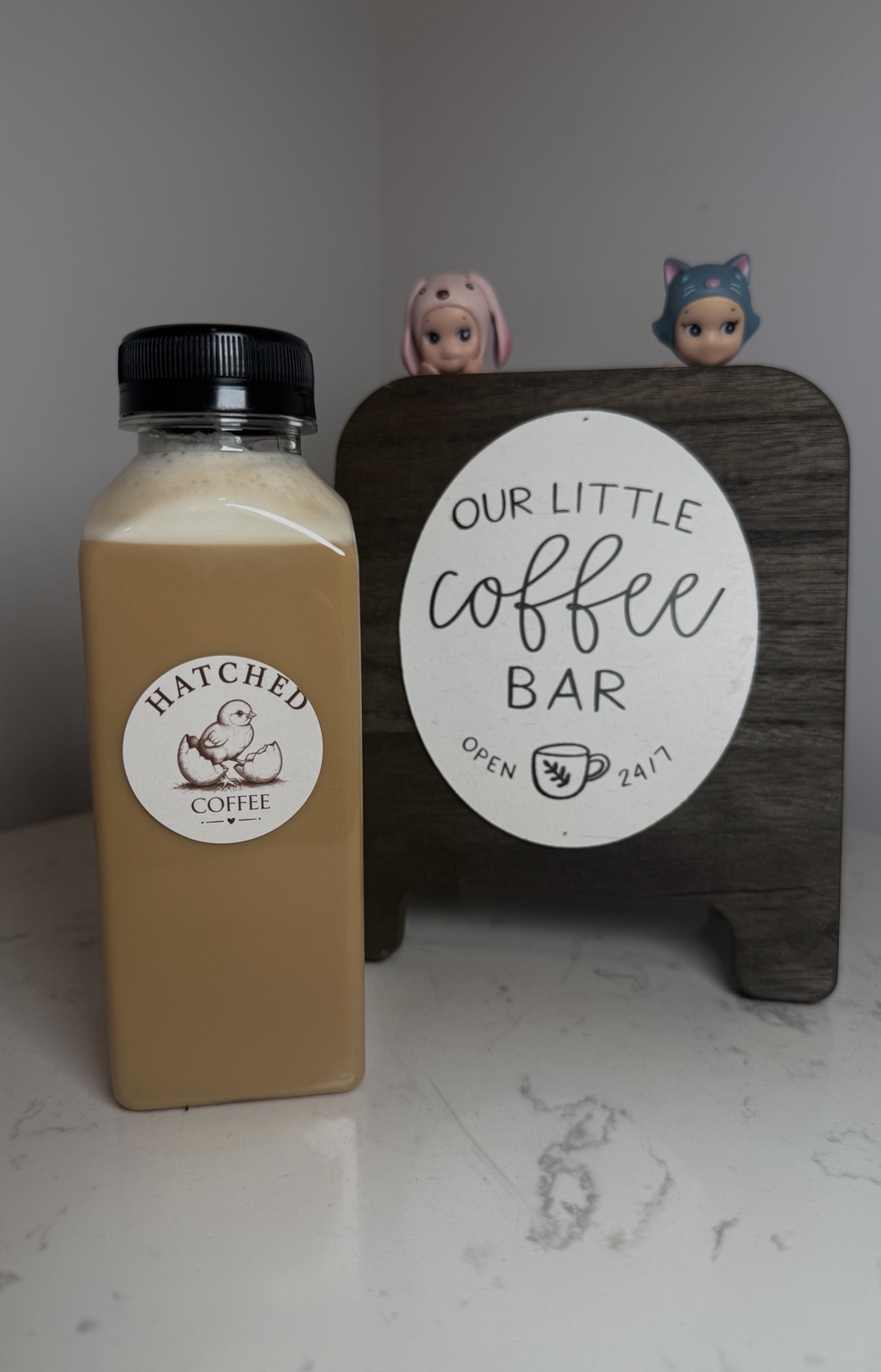 Hatched Coffee bottled latte beside an Our Little Coffee Bar sign